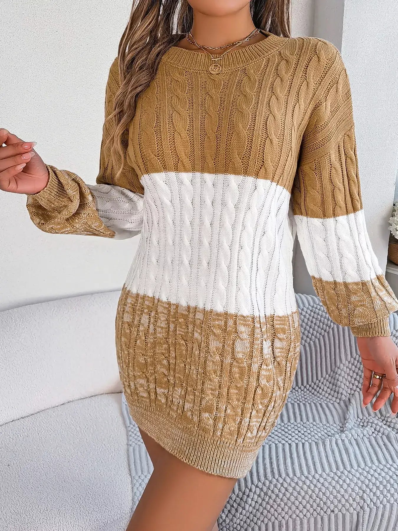 Woman wearing a color block cable knit sweater dress with textured pattern, featuring slightly stretchy 100% acrylic material.