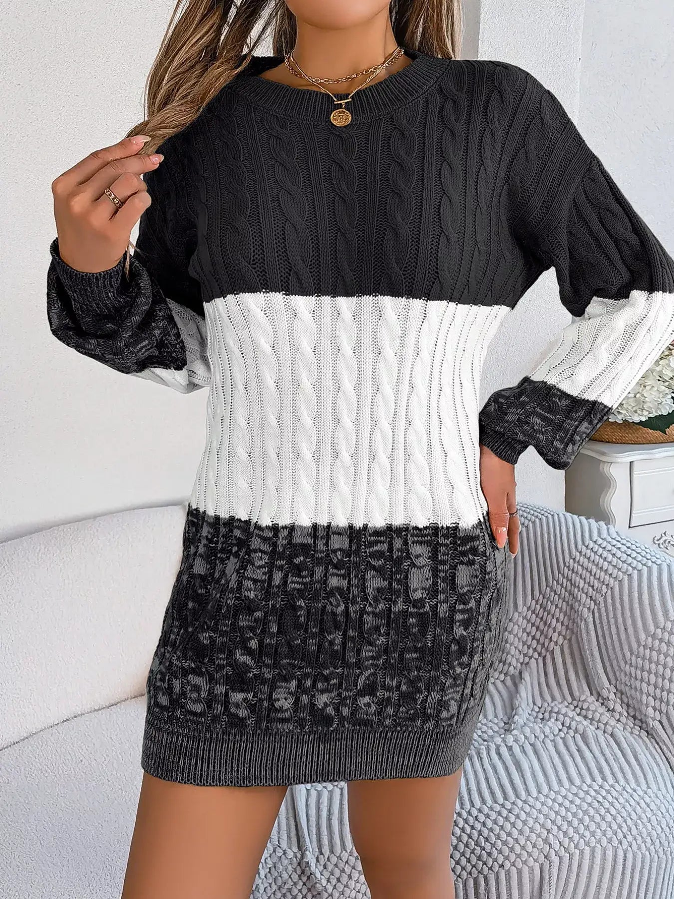 Woman wearing color block cable knit sweater dress with textured pattern in black, white, and gray, slightly stretchy 100% acrylic.