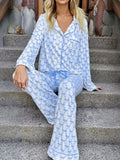 Woman wearing Felvior Bow Print Pajama Set, long sleeve shirt and pants, sitting on steps.