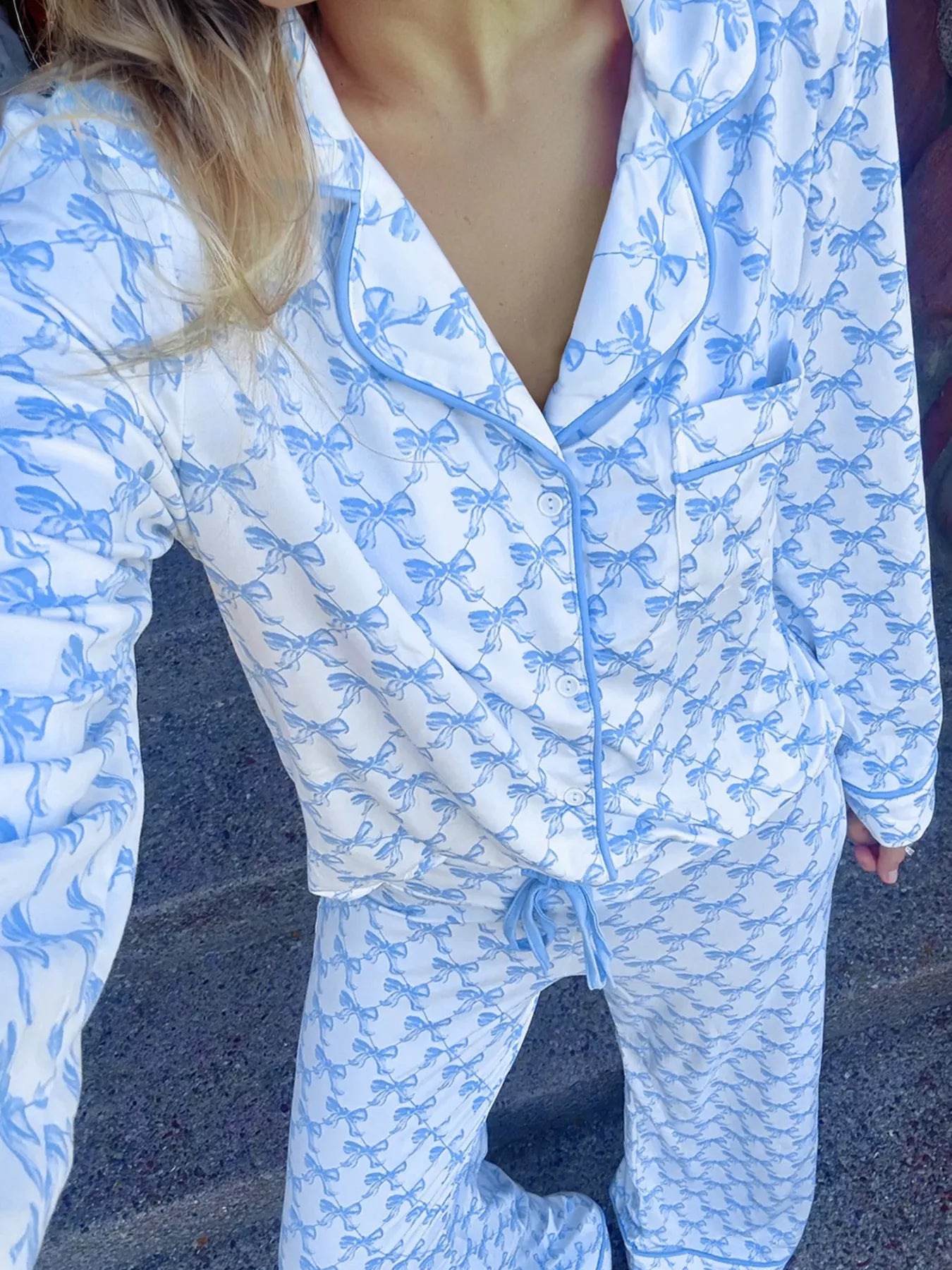 Woman wearing Bow Print Pajama Set from Felvior, featuring long-sleeve shirt and pants with bow design.