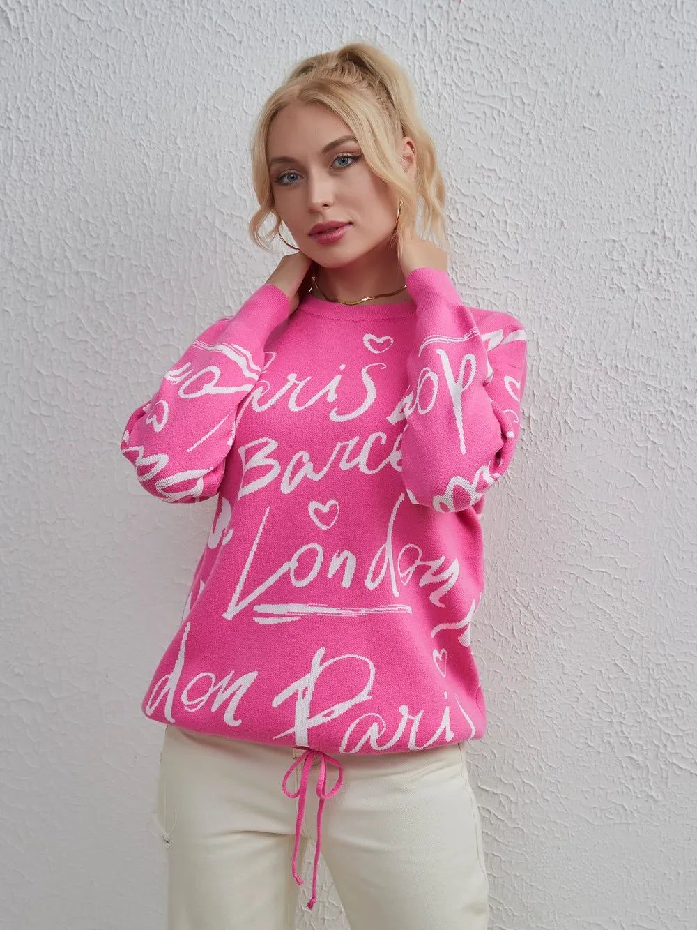Model wearing pink Letter Pattern Sweater with drawstring hem and dropped shoulder style against white wall