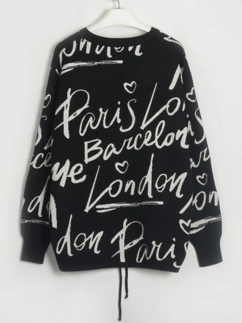 Back view of a Letter Pattern Sweater with black fabric, letter design, and drawstring hem.