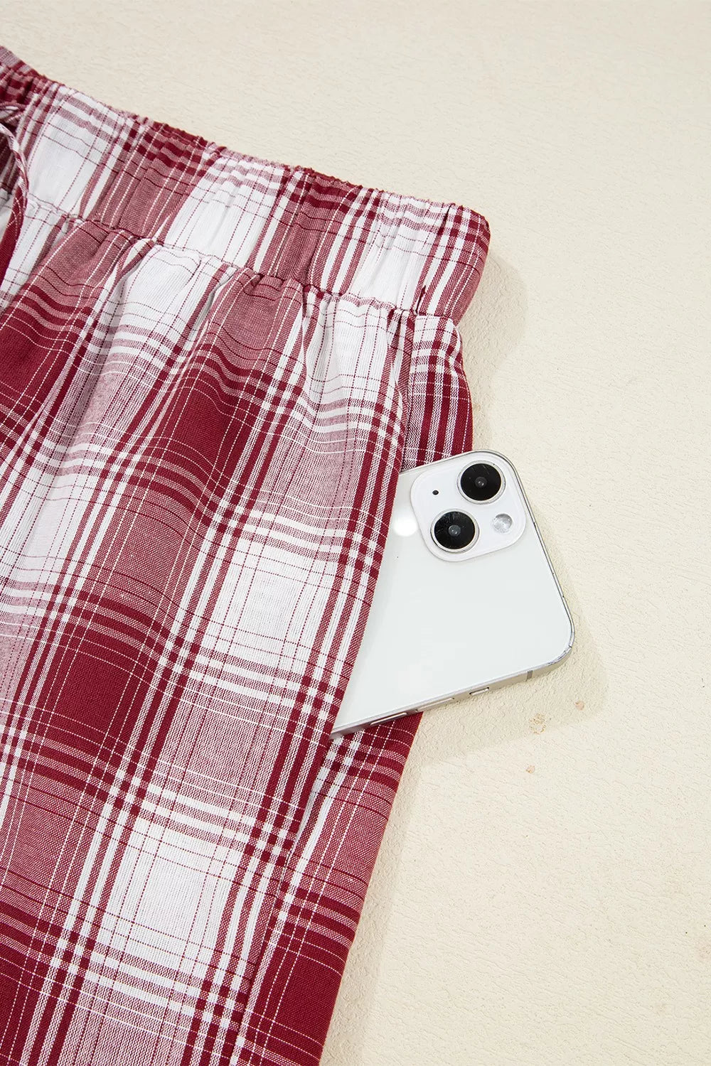 Close-up of plaid design drawstring shorts from Plaid Long Sleeve Lounge Set with phone in pocket.