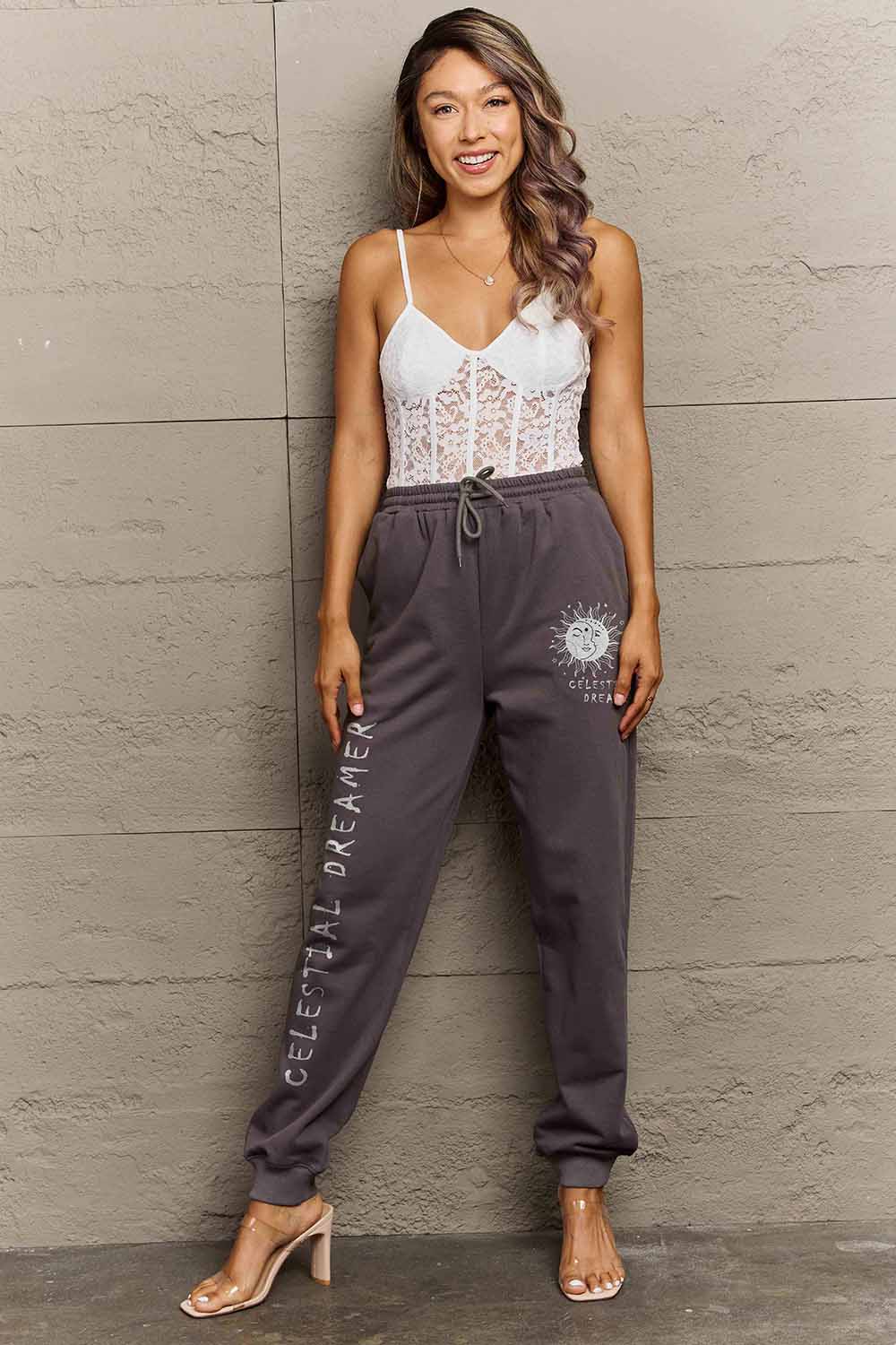 Woman wearing Graphic Sweatpants with CELESTIAL DREAMER print, showcasing a relaxed style.