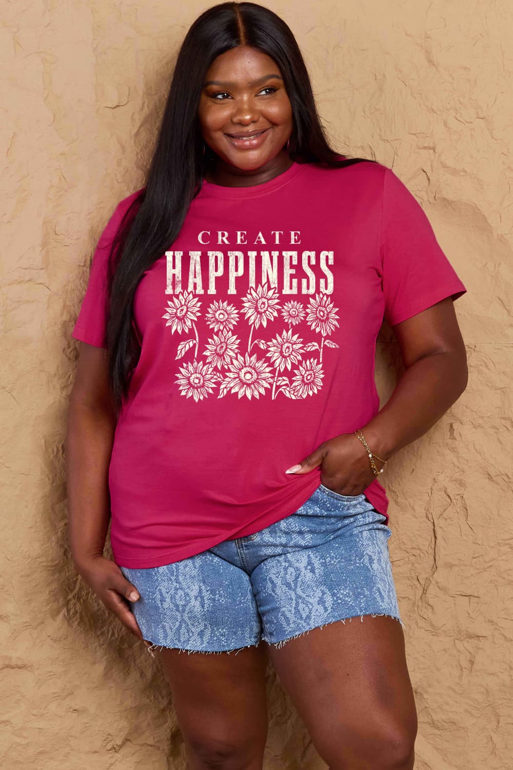 Woman wearing a Graphic Cotton T-Shirt with 'CREATE HAPPINESS' print and floral design, paired with denim shorts, casual style