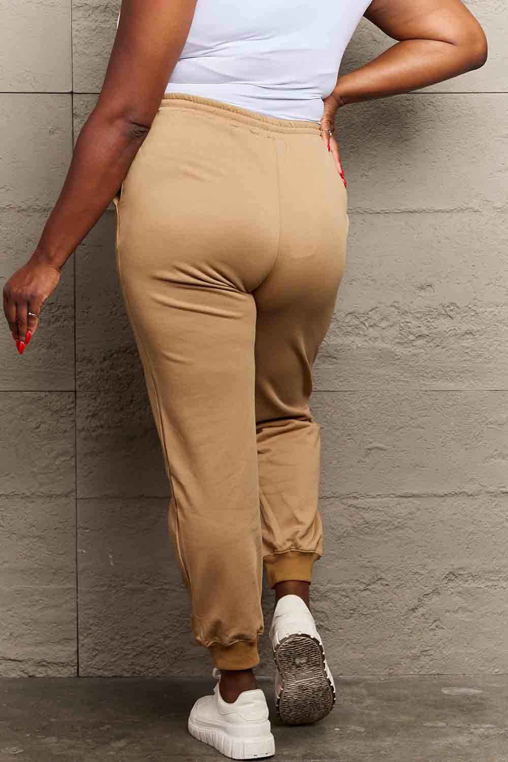Rear view of person wearing Graphic Sweatpants in beige, showcasing comfortable fit and ankle cuffs.