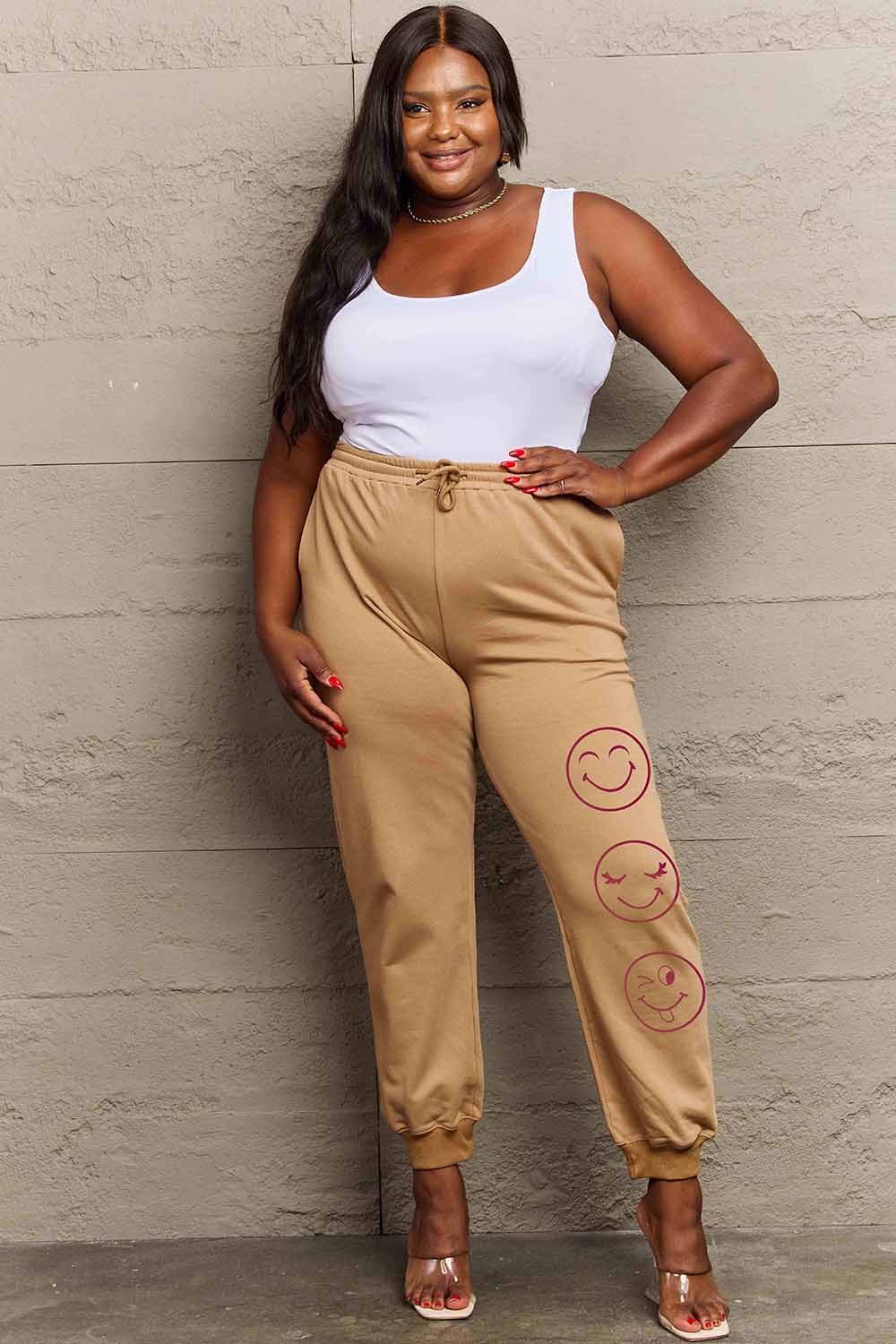 Woman wearing Graphic Sweatpants with emoji print, featuring a relaxed fit and drawstring waist for stylish comfort in casual wear.