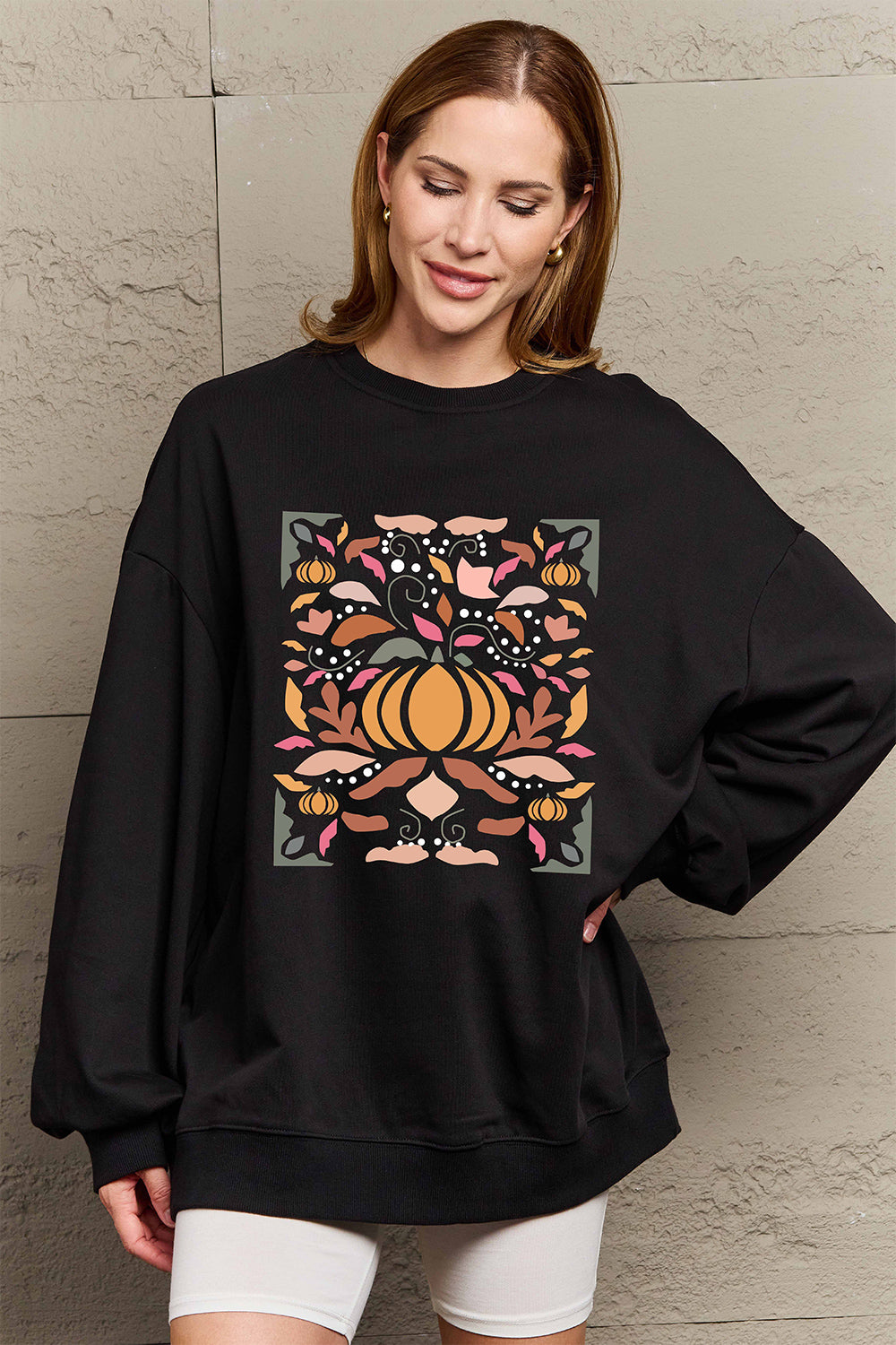 Woman wearing Graphic Dropped Shoulder Sweatshirt with pumpkin print, showcasing casual style and comfort for everyday wear.