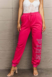 Woman wearing Graphic Sweatpants with PINK print, showcasing drawstring waistband and relaxed fit, ideal for style and comfort.