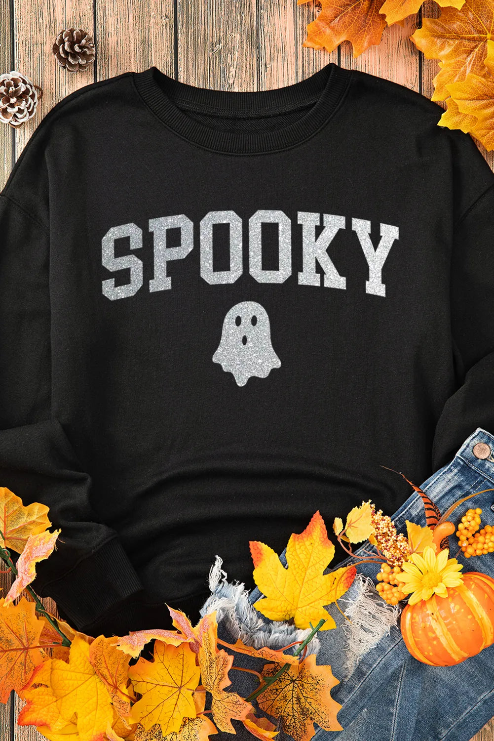 Spooky Sweatshirt with glitter detail, round neck, and long sleeves, surrounded by autumn leaves and casual denim.
