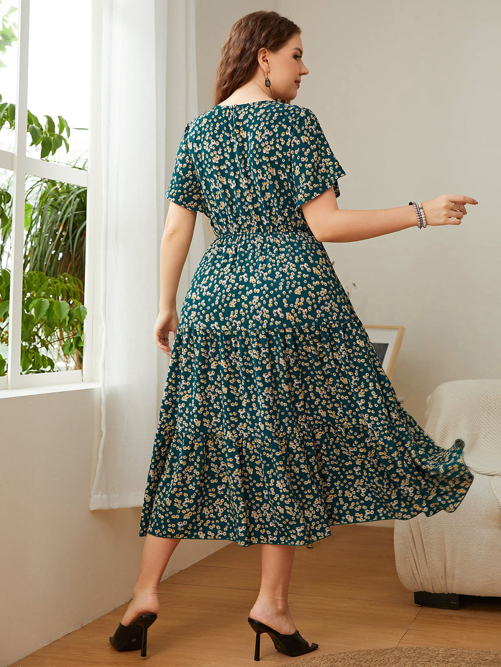 Woman wearing plus-size Floral Midi Dress with round neckline and flutter sleeves, showcasing the floral pattern and A-line silhouette.