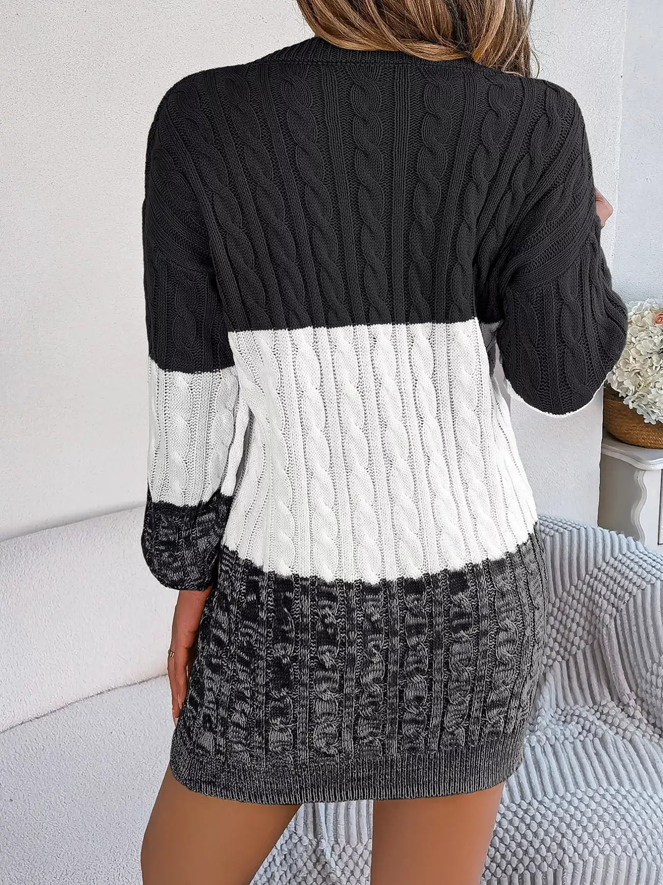 Back view of color block cable knit sweater dress with textured pattern in black, white, and grey colors.