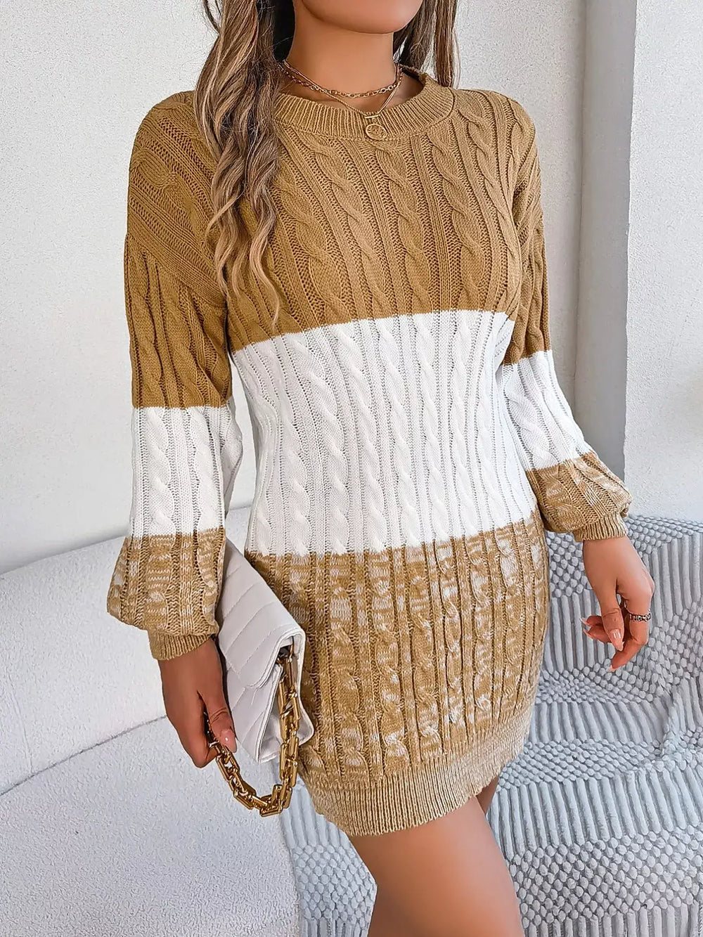 Woman wearing color block cable knit sweater dress with textured pattern, featuring basic cable-knit style and slight stretch in acrylic fabric.